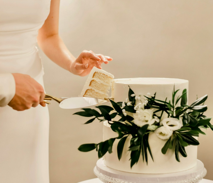 A woman cutting her wedding cake made by Kelly Ann Creations